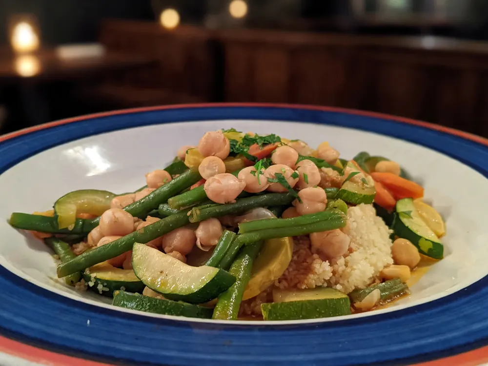 Green beans, chickpeas, zucchini and carrot over couscous on a blue-rimmed plate