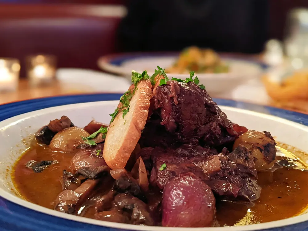 Braised beef with mushrooms, pearl onions and a toast slice in brown sauce
