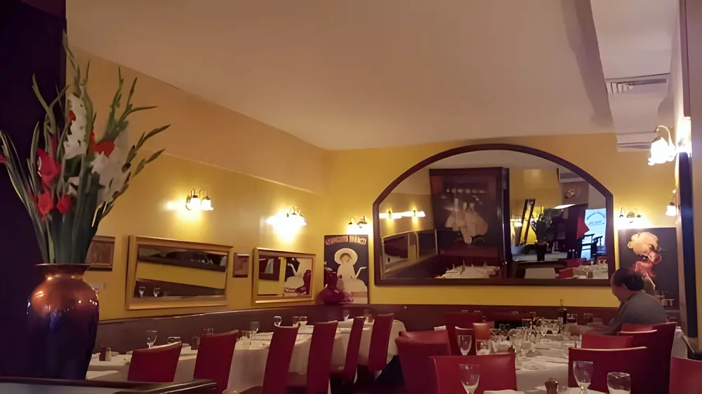 Dining room with yellow walls, arched mirror, vintage posters and tables set with white linens