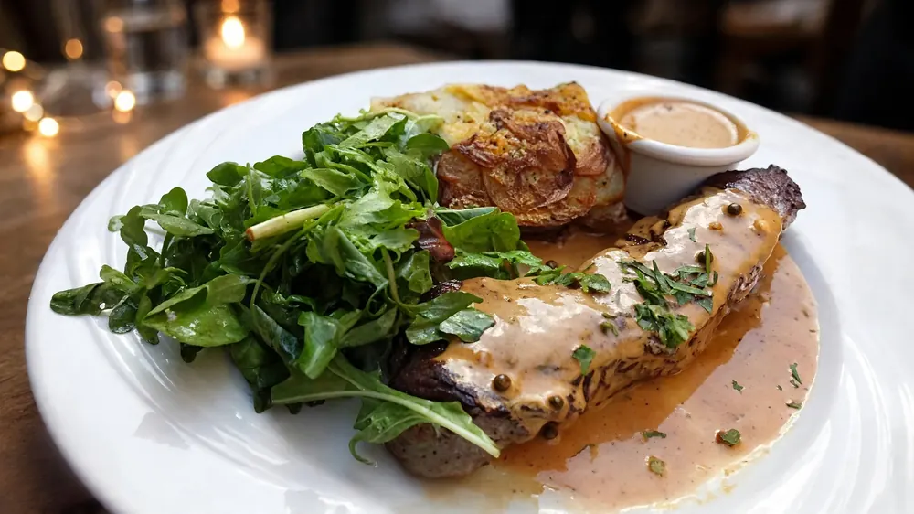 Sliced steak in peppercorn sauce with arugula salad and a gratin