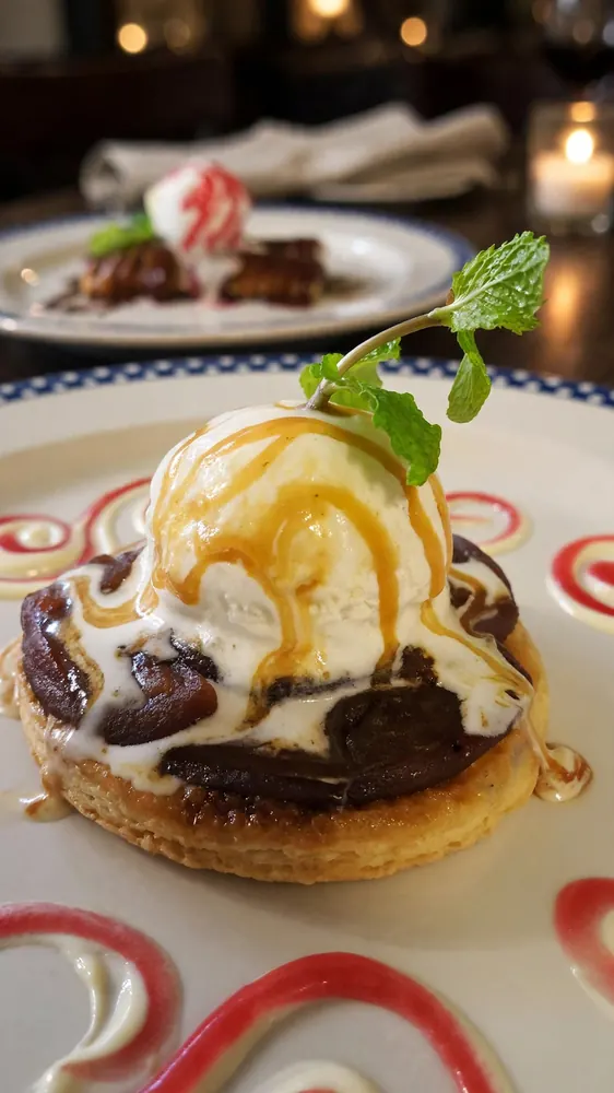 Scoop of vanilla ice cream with caramel and mint on a chocolate pastry round