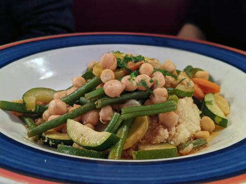 Green beans, chickpeas, zucchini and carrot over couscous on a blue-rimmed plate