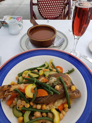 Blue-rimmed plate of braised meat with green beans and chickpeas, beside a glass of rosé
