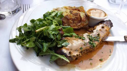 Sliced steak in peppercorn sauce with arugula salad and a gratin