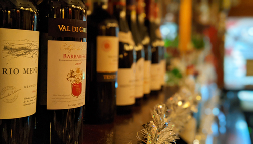 Row of Italian red wine bottles on a bar with tinsel